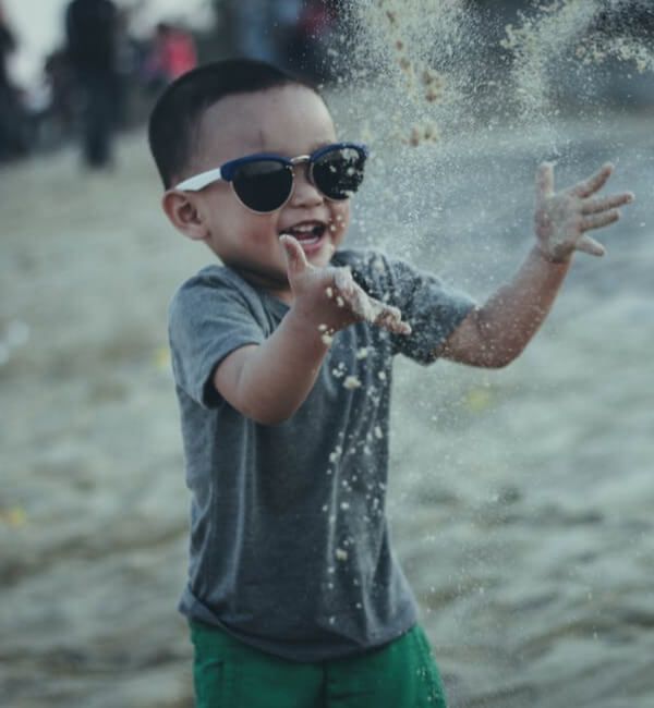 image of young boy on the beach wearing sunglasses