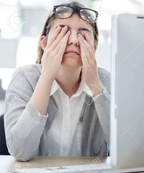 Image of a woman rubbing her eyes at her desk
